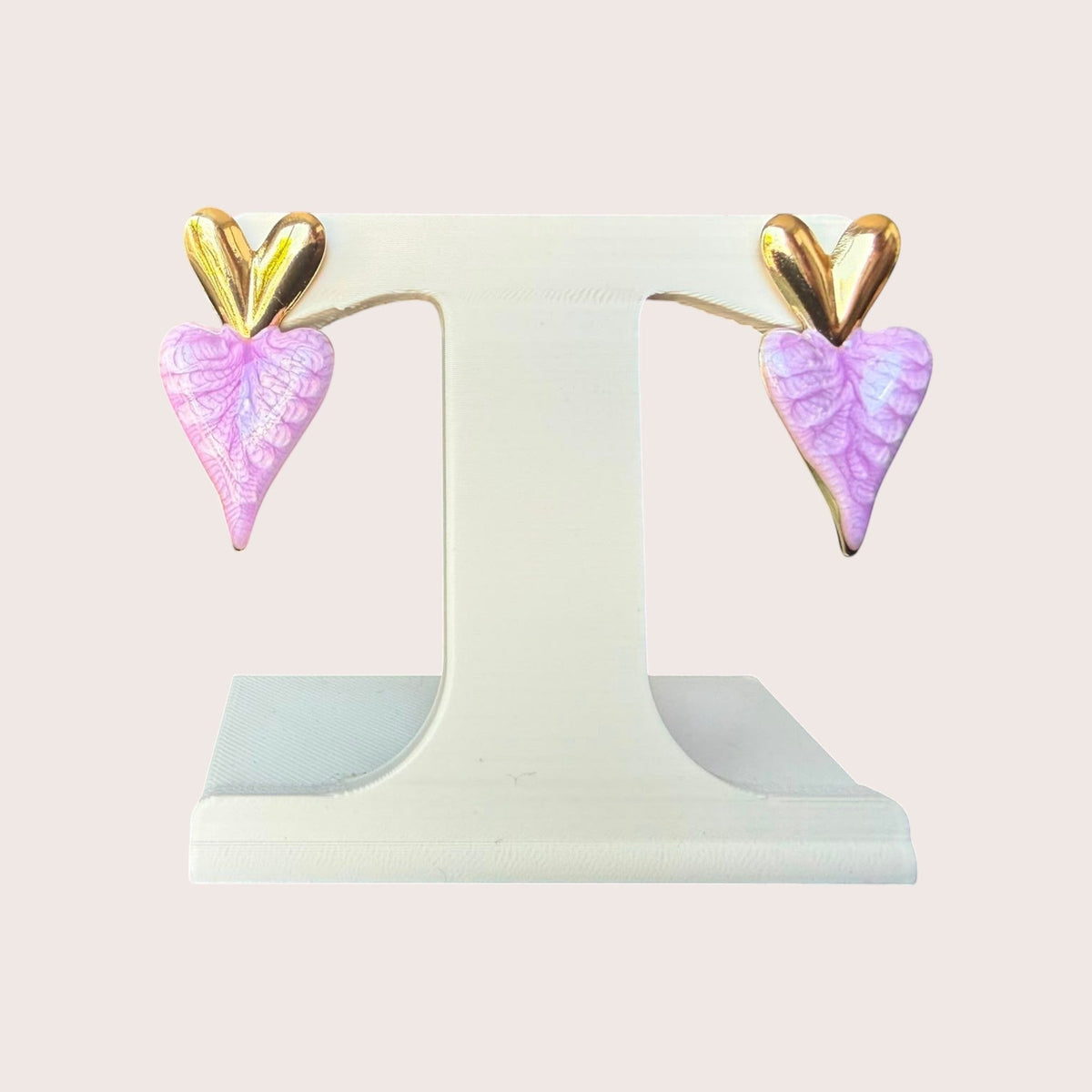 Nitelief Amour Rose dangling heart earrings featuring textured pink heart charms with gold accents on a display stand.