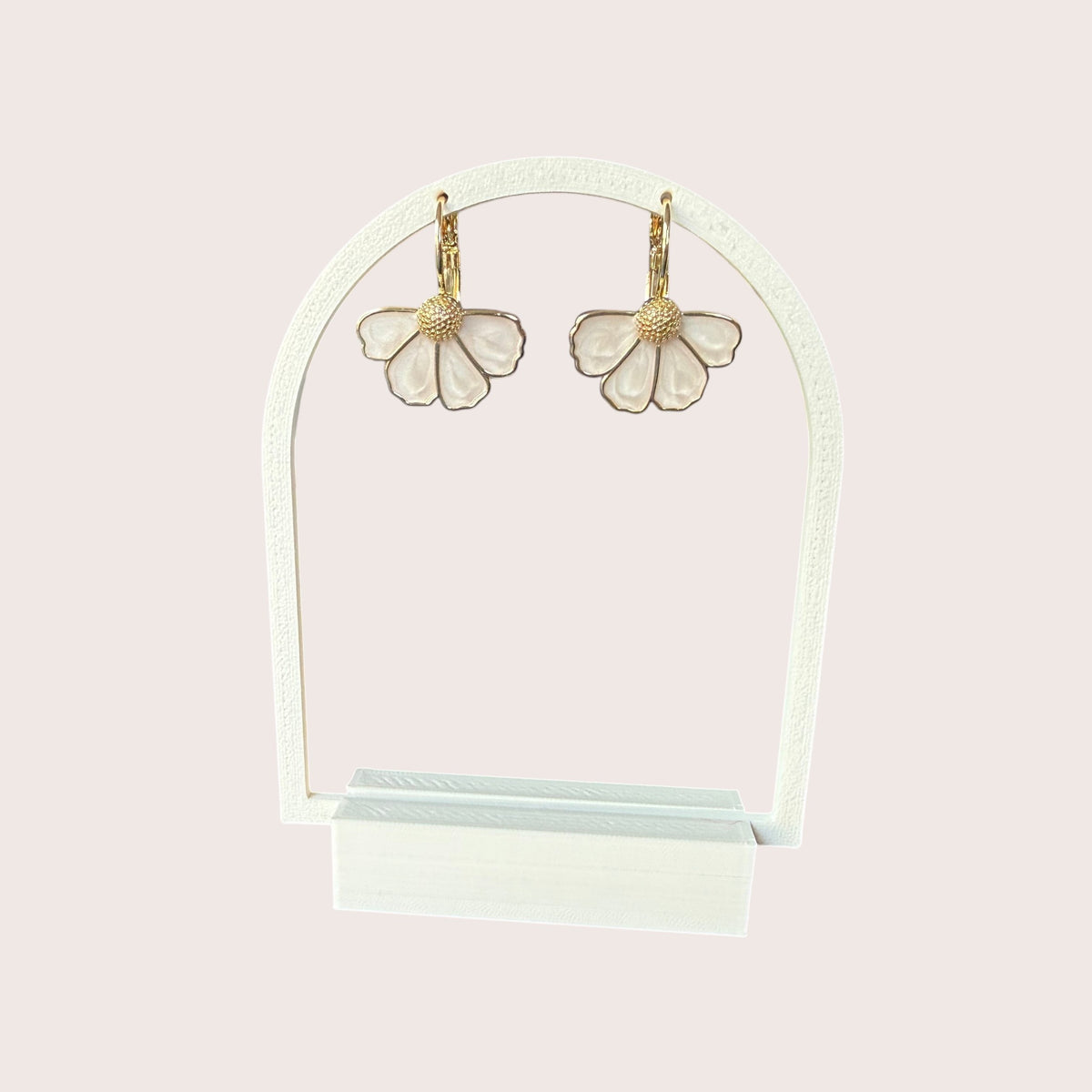 Nitelief bloem flower-shaped drop earrings with white petals and gold-tone textured centers on a display stand
