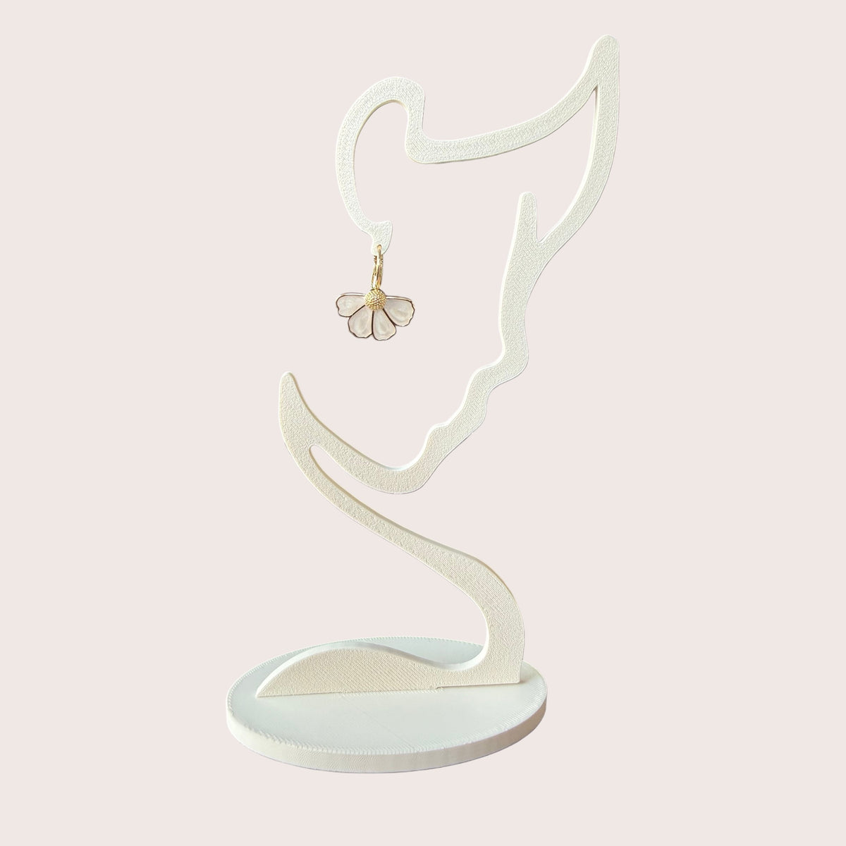Nitelief bloem flower-shaped earring with white petals and gold center hanging on a minimalist face-shaped stand