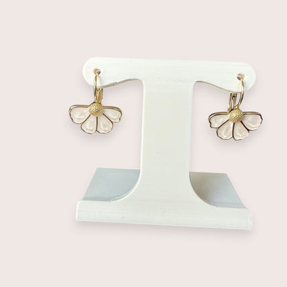 Nitelief bloem flower-shaped earrings with white enamel petals and gold-tone centers on a display stand