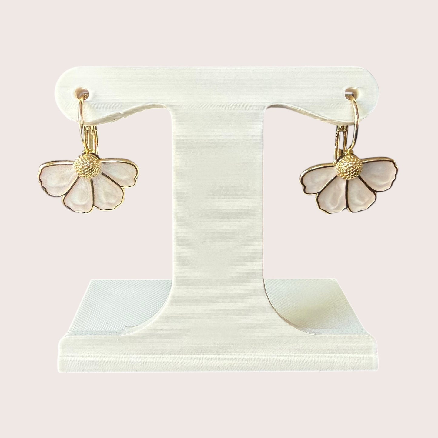 Nitelief bloem flower-shaped drop earrings with white petals and gold textured centers on a display stand