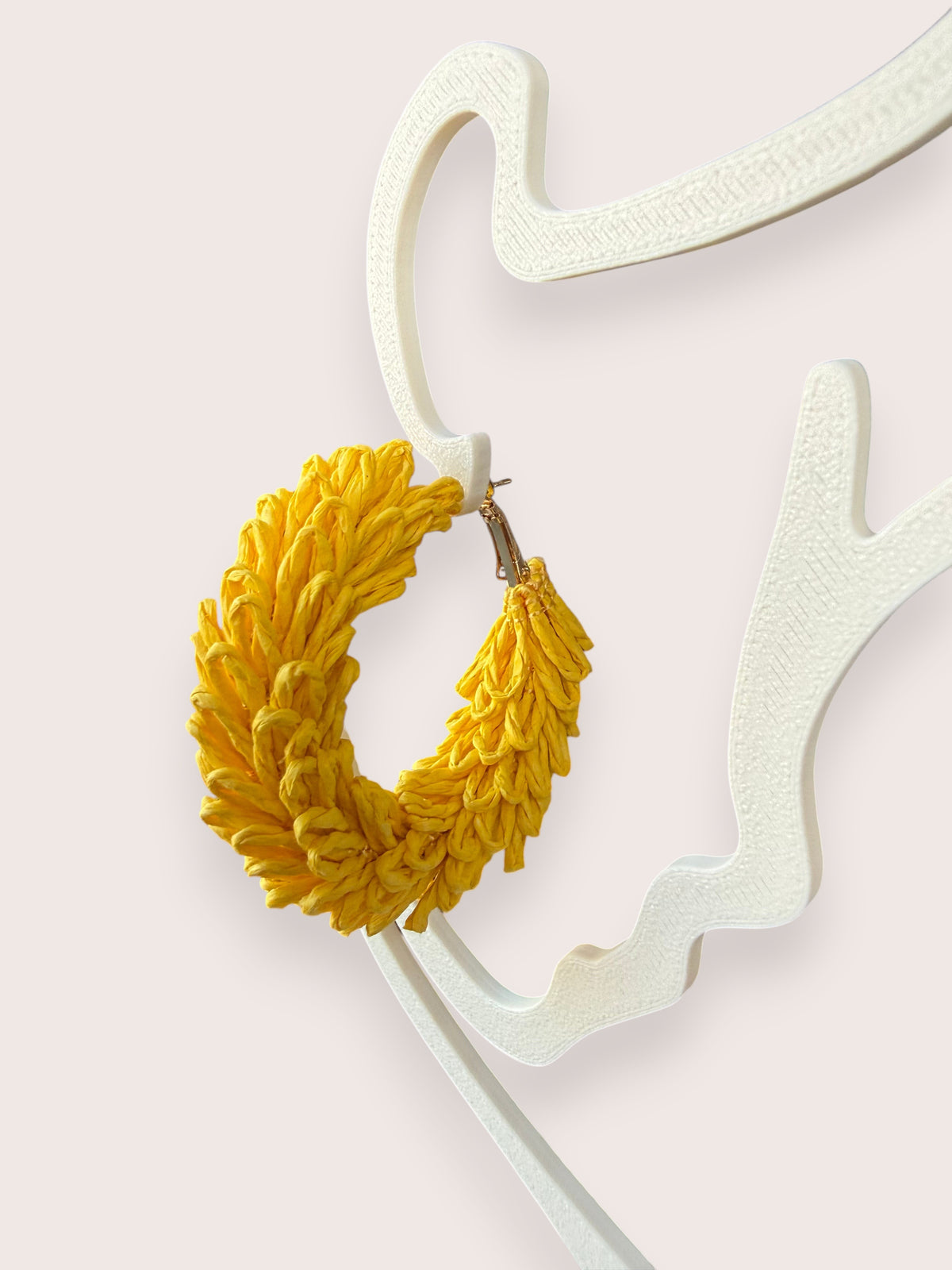 Nitelief CONCEPT Volle maan lightweight yellow raffia hoop earrings displayed on a white abstract stand