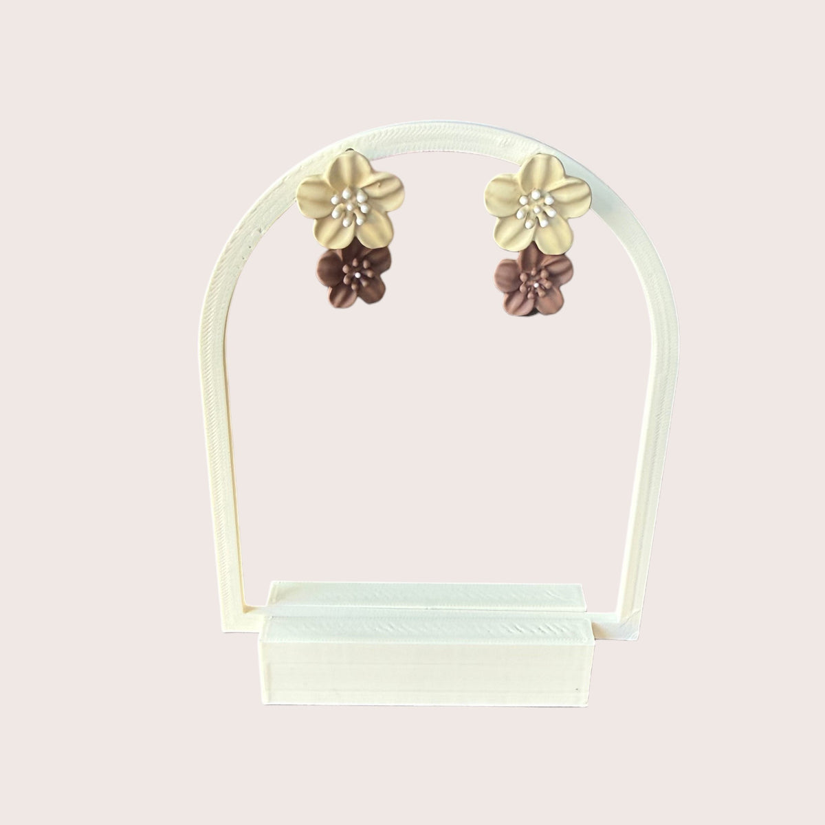 Nitelief double flower earrings in beige and brown with pearl centers displayed on a white stand