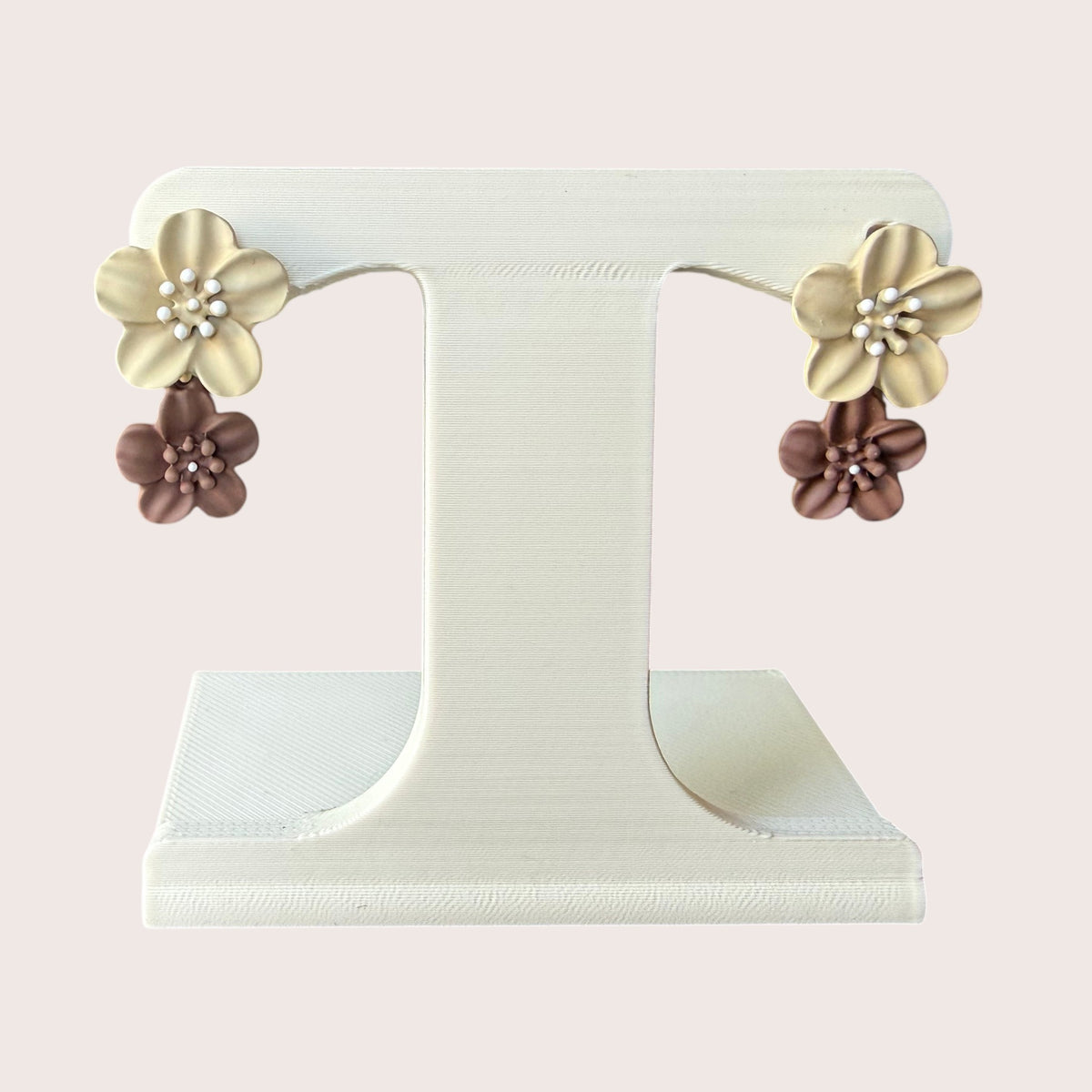 Nitelief double flower earrings featuring layered cream and brown matte floral charms on a white display stand.