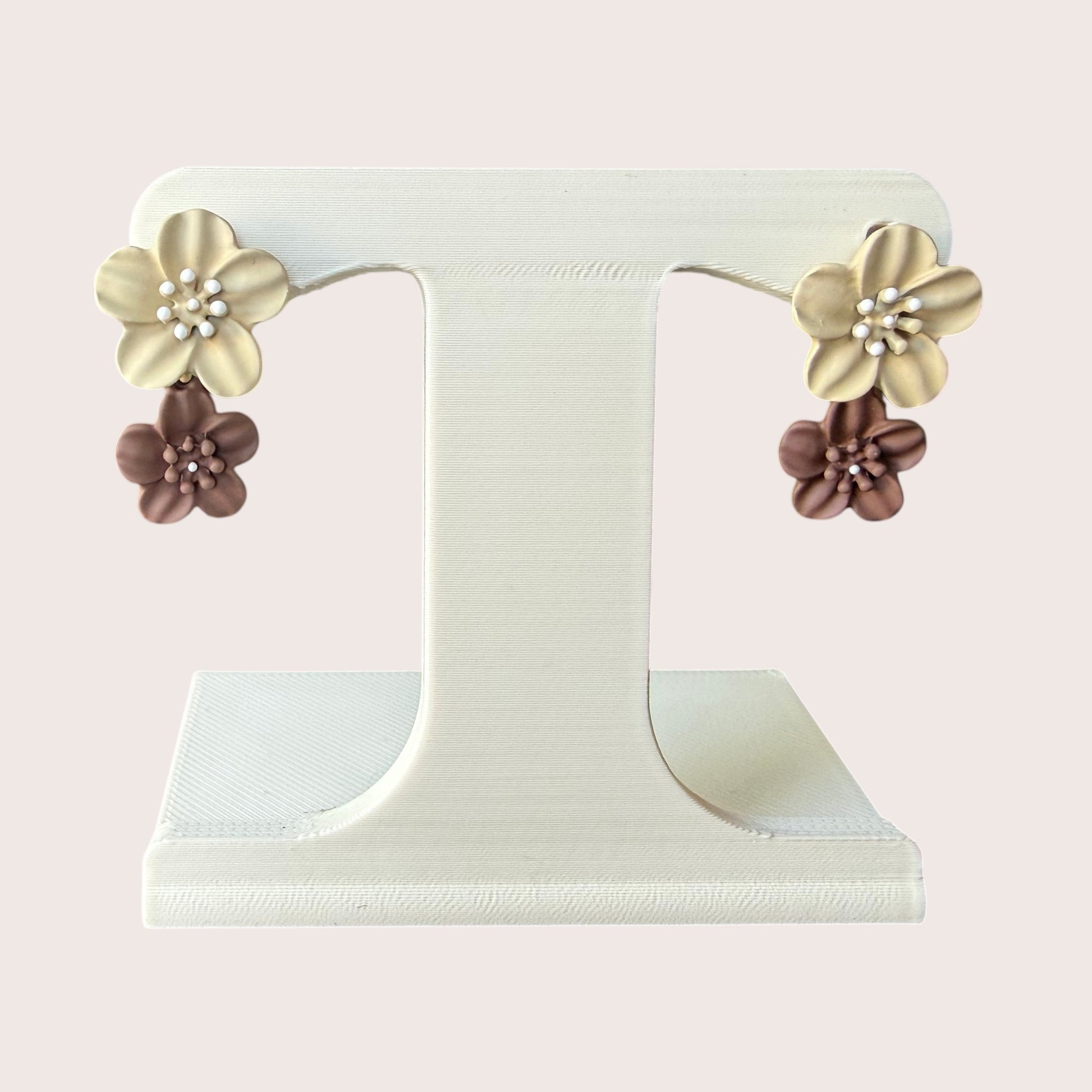 Nitelief double flower earrings featuring layered cream and brown matte floral charms on a white display stand.