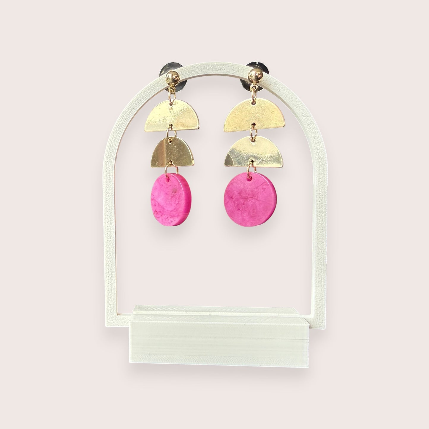 Nitelief gold-tone metal and pink resin geometric drop earrings on a white arch display stand