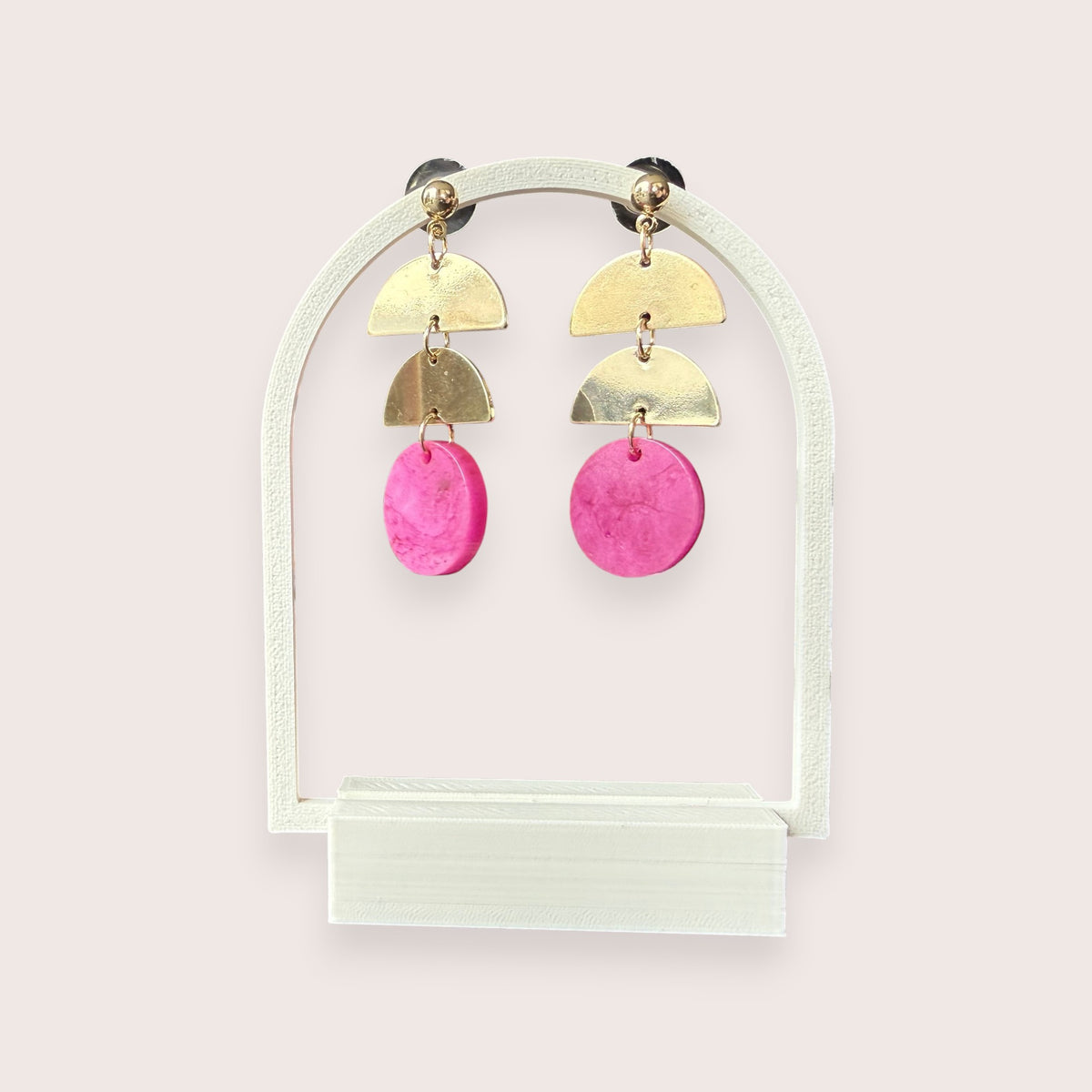 Nitelief gold-tone metal and pink resin geometric drop earrings on a white arch display stand