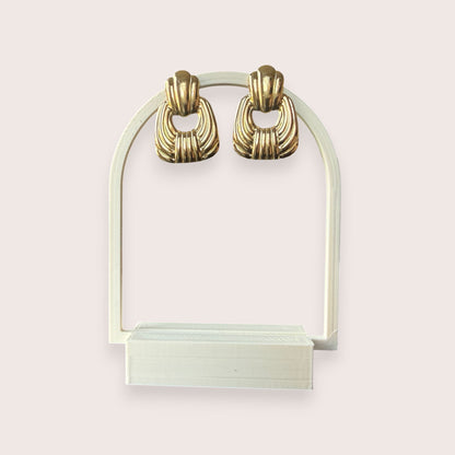 Nitelief gold-toned vintage style statement earrings with a ribbed shell-inspired design on a display stand.