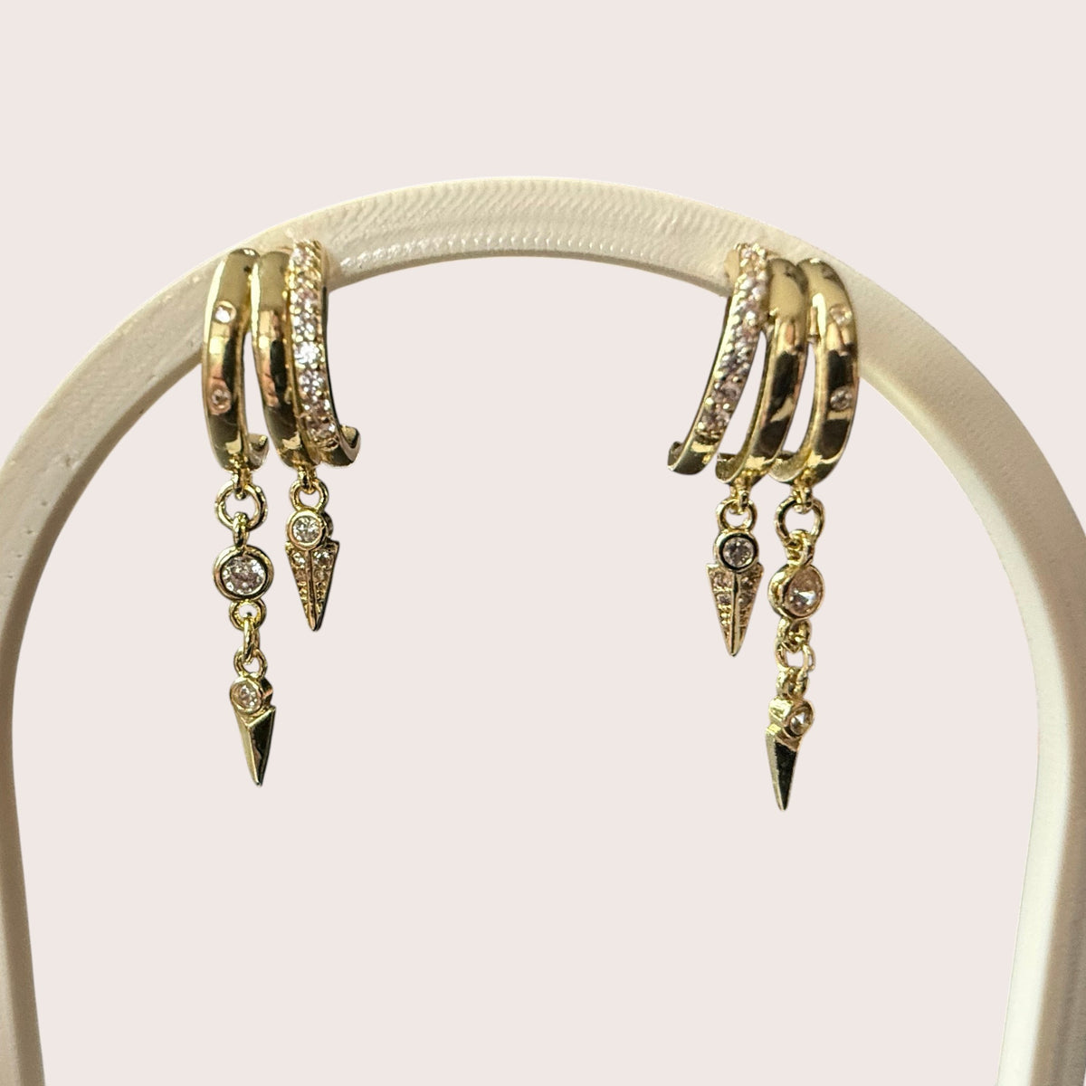 Nitelief gold hoop earrings with dangling spike charms and sparkling cubic zirconia accents on a display stand
