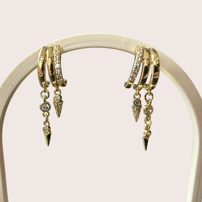 Nitelief gold hoop earrings with dangling spike charms and sparkling cubic zirconia accents on a display stand