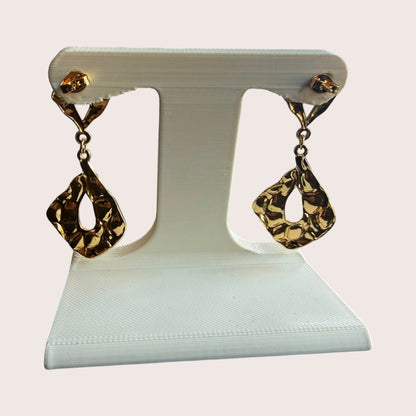 Nitelief Lilas gold-toned drop earrings with a textured, organic teardrop shape displayed on a white stand.