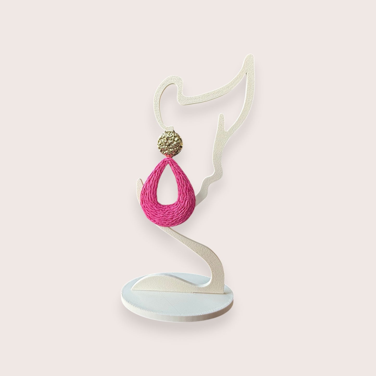 Nitelief bohemian style pink woven raffia teardrop earring with a gold textured stud on a white display stand