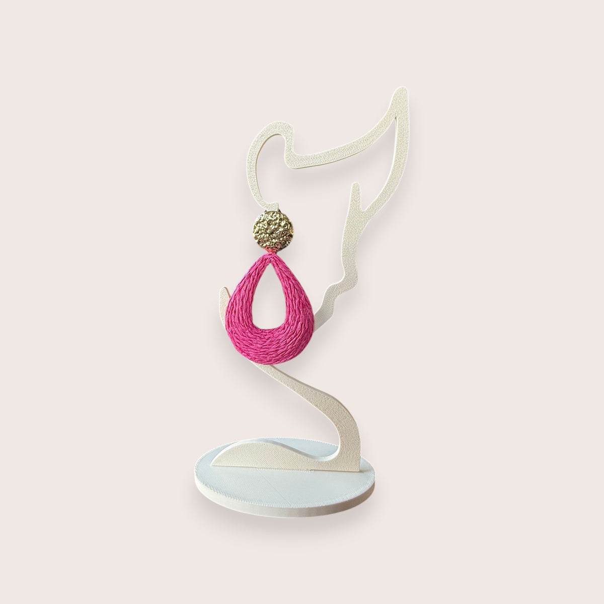 Nitelief bohemian style pink woven raffia teardrop earring with a gold textured stud on a white display stand