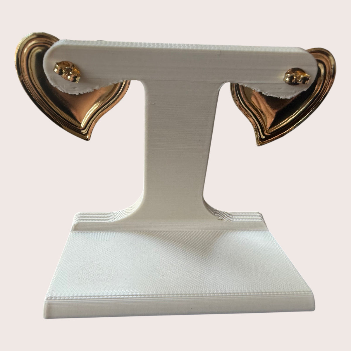 Nitelief purple heart-shaped earrings with gold-tone metal edges displayed on a white stand