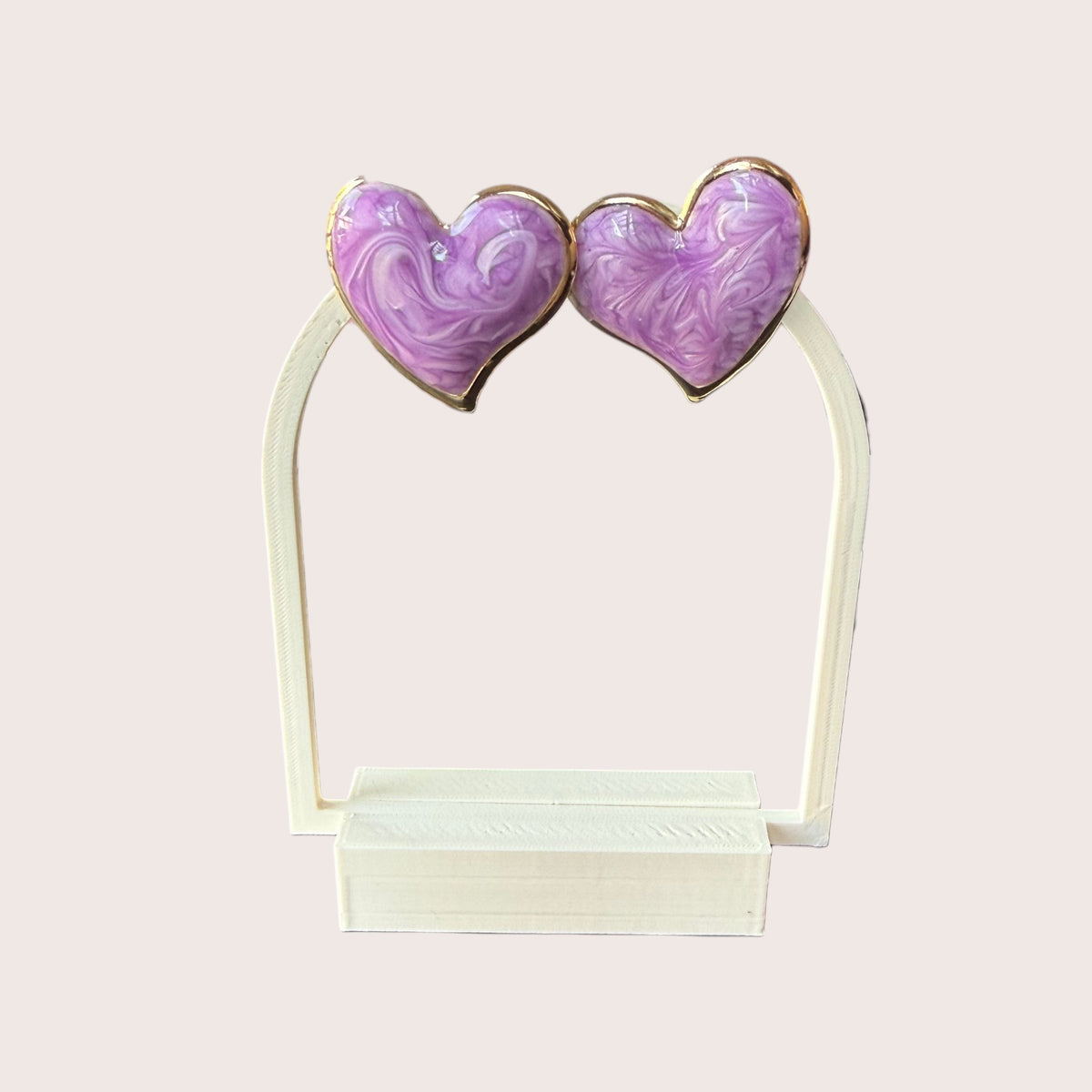 Nitelief pair of purple marbled heart-shaped earrings with gold trim displayed on a white stand