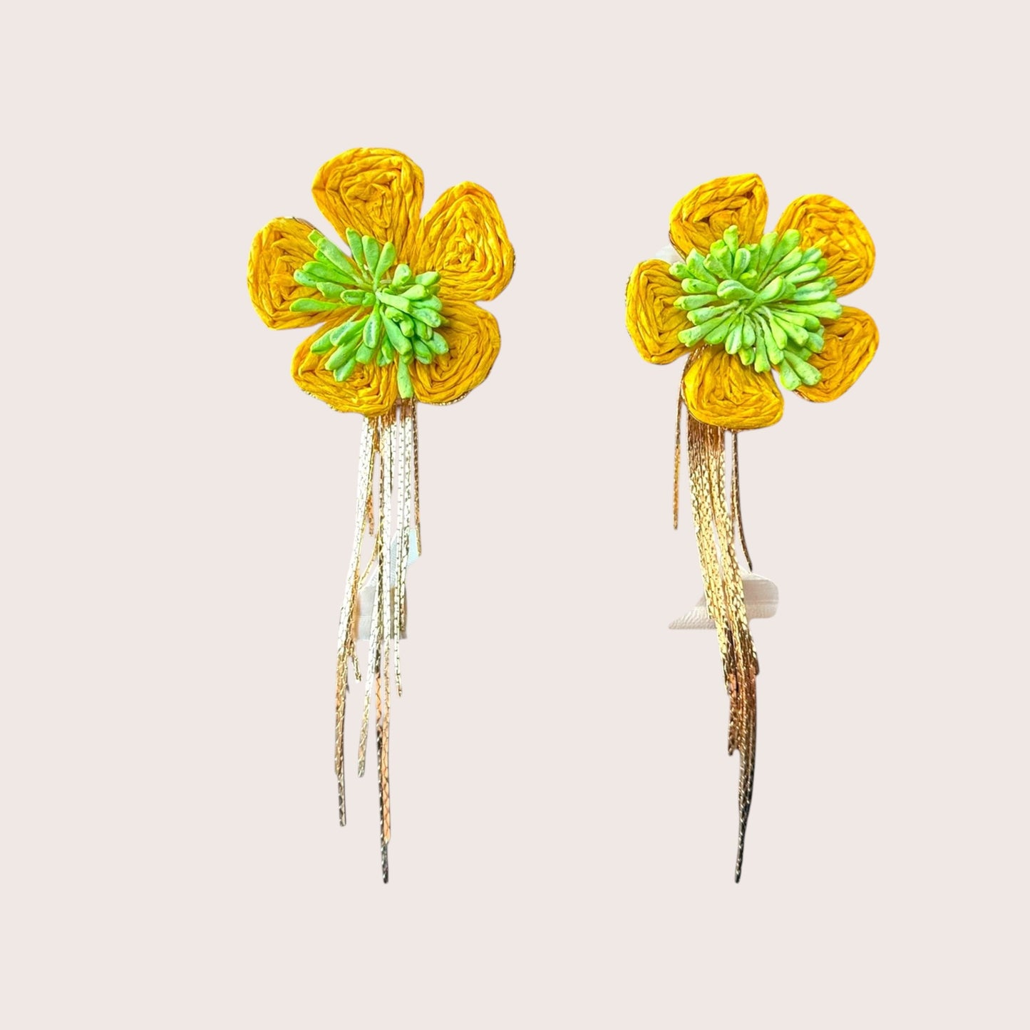 Nitelief Soleil raffia flower earrings in yellow with green centers and dangling gold-tone metallic fringe details.