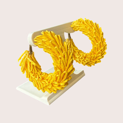 Nitelief CONCEPT Volle maan lightweight yellow raffia hoop earrings with a textured woven design on a display stand