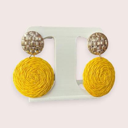 Nitelief CONCEPT Zonnetje earrings featuring round yellow raffia discs hanging from textured gold-tone metal studs.
